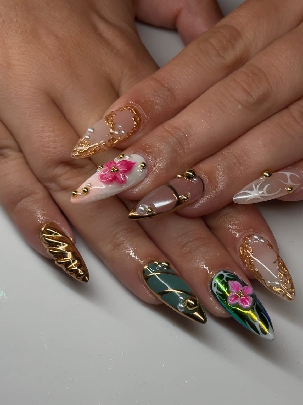 Almond Gel-X set with 3D pink hibiscus, gold chrome swirls and dark green accents