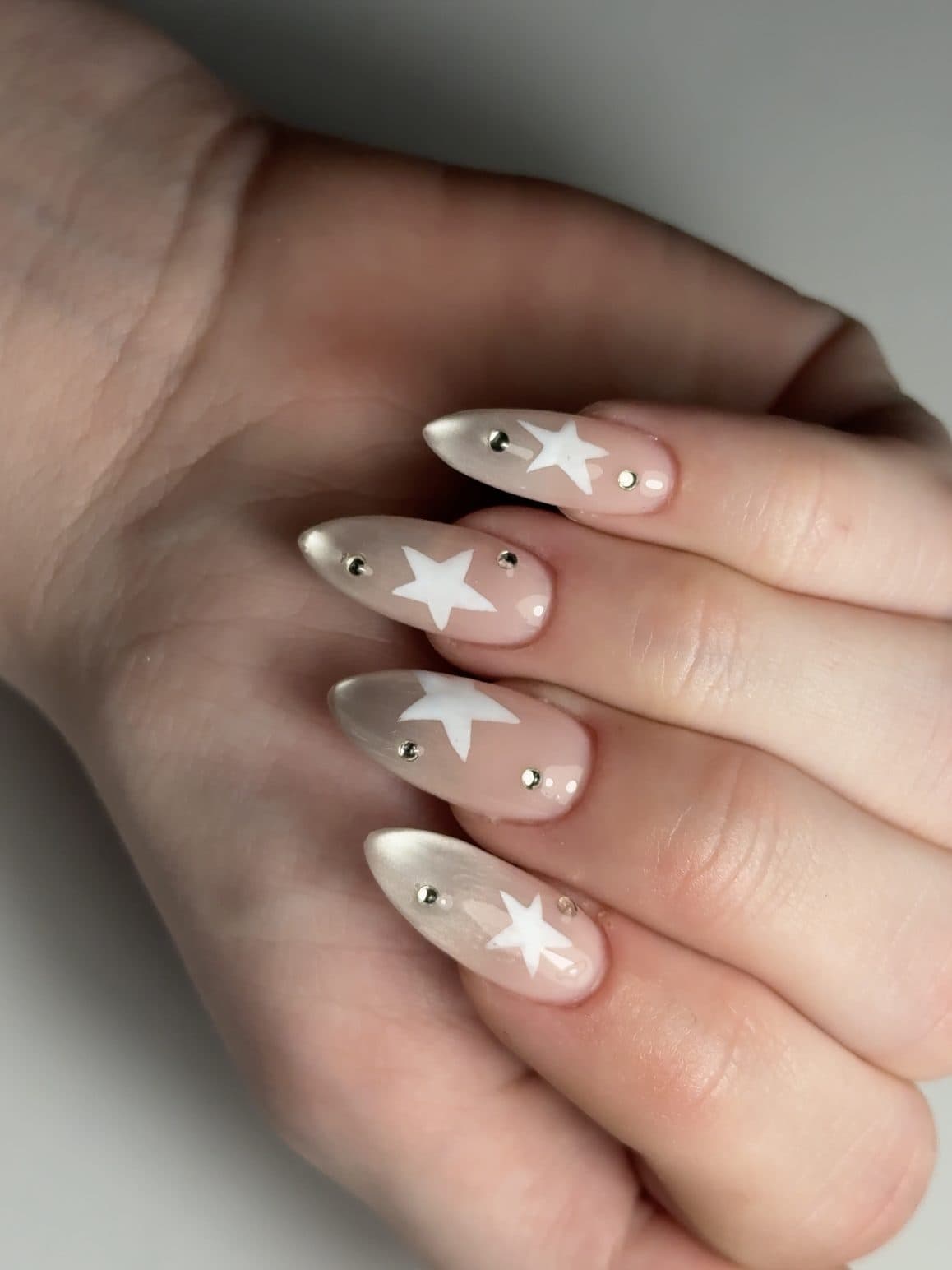 Milky white almond Gel-X nails with white star decals and crystal studs