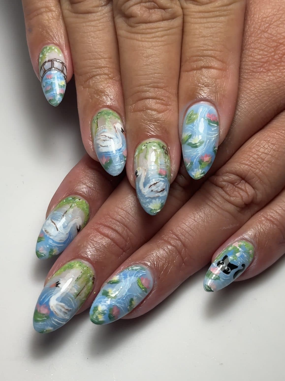 Monet-inspired hand-painted almond Gel-X nails with blue skies, greenery and water lilies