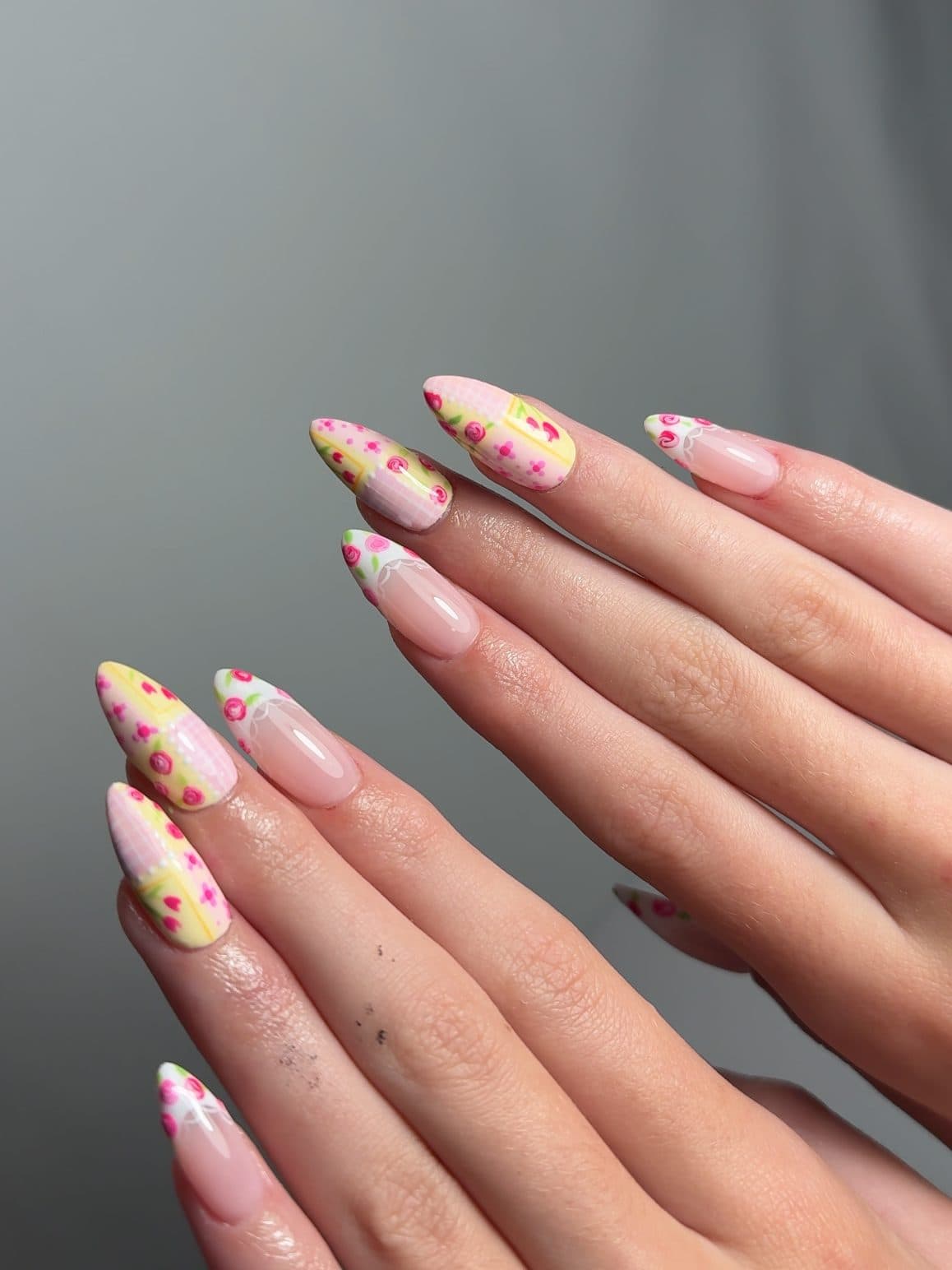 Pale pink almond Gel-X nails with hand-painted yellow and pink flowers