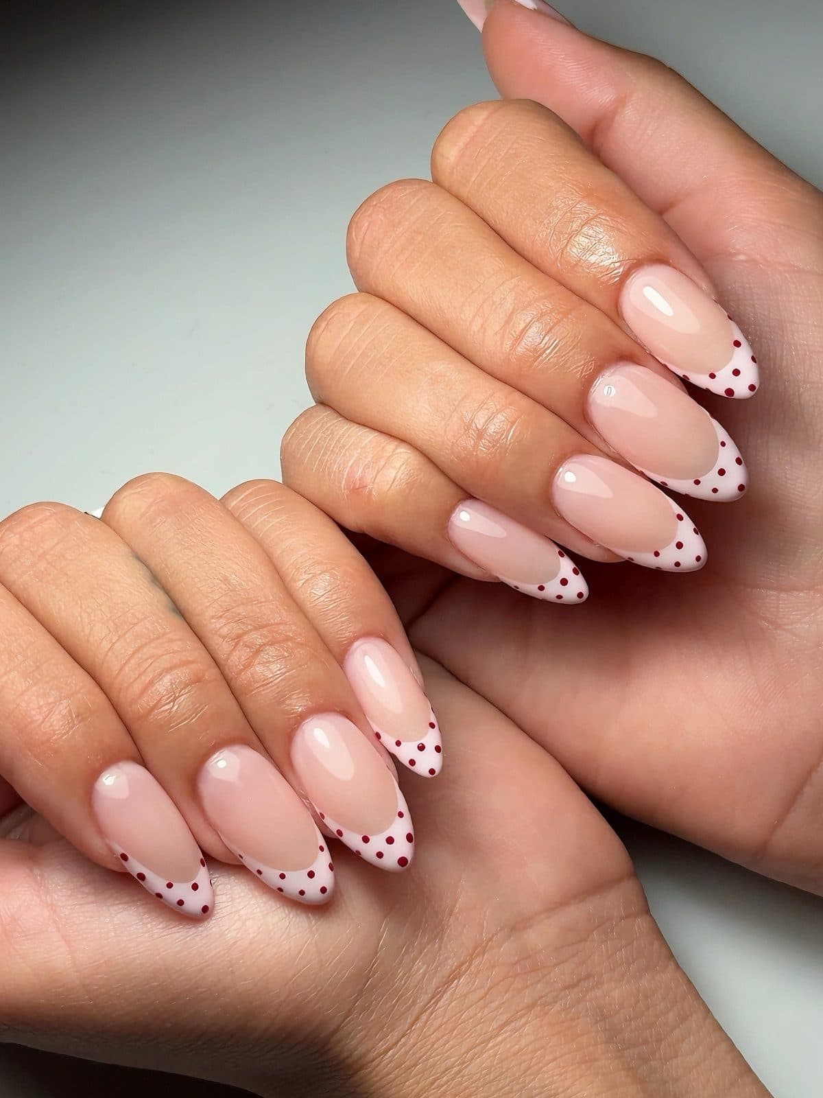 Soft pink almond Gel-X nails with tiny black dot French tips