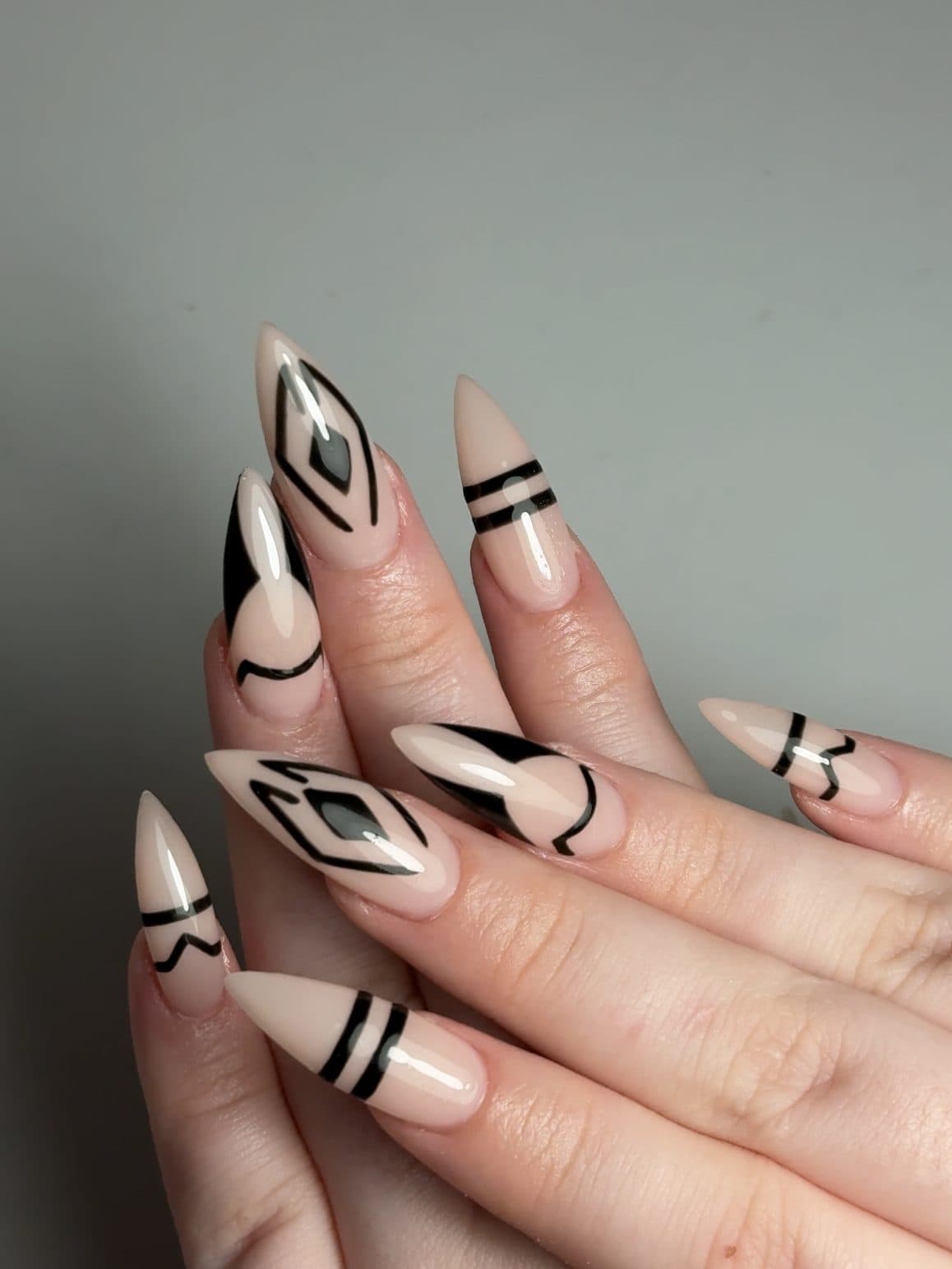 Nude stiletto Gel-X nails with bold black geometric line art