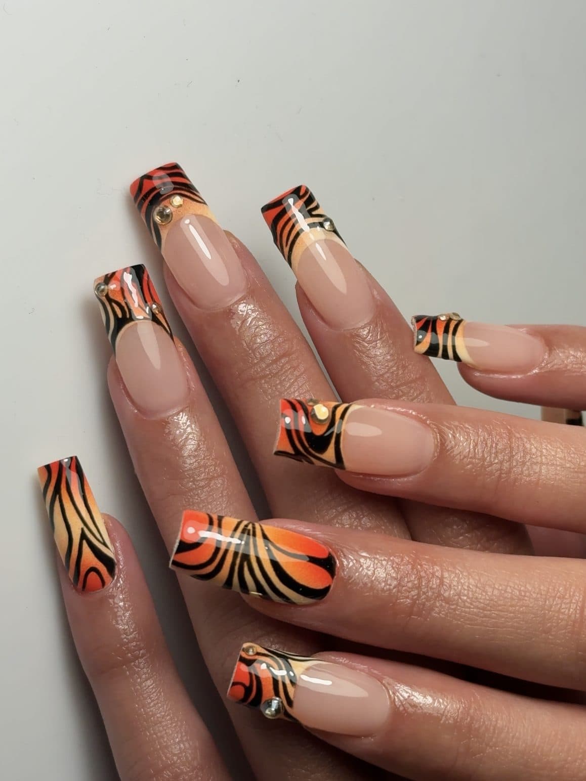 Square Gel-X nails with orange and black tiger stripe French tips